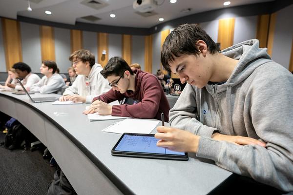 学生们坐在教室里的长课桌前