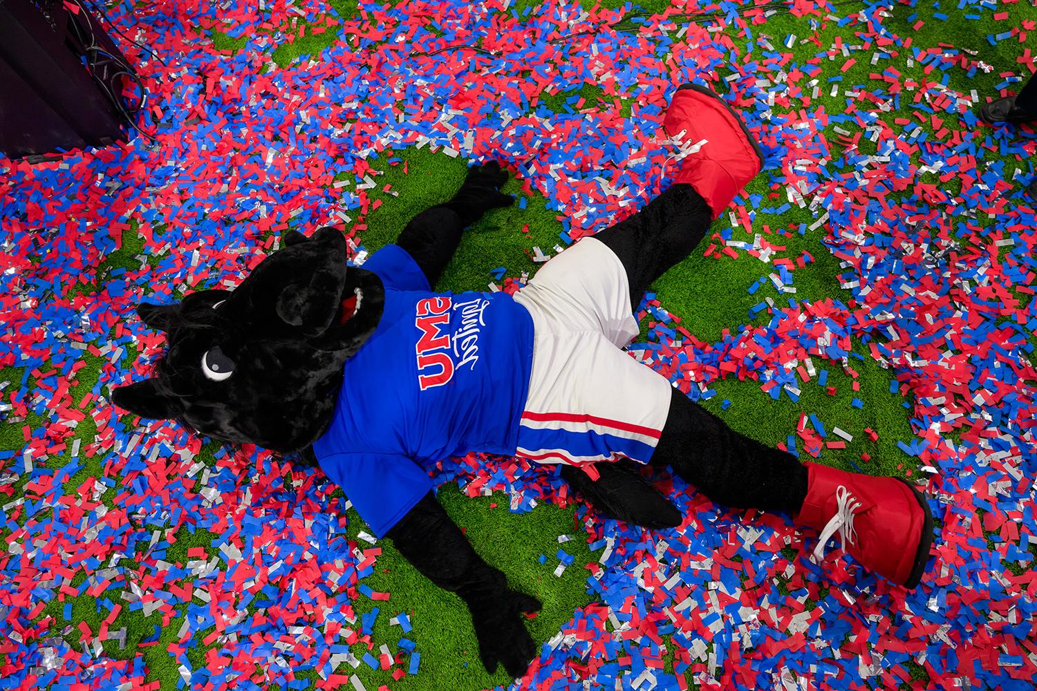 Peruna mascot laying on a floor covered in confetti.